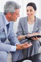 Smiling business people working and talking together on sofa