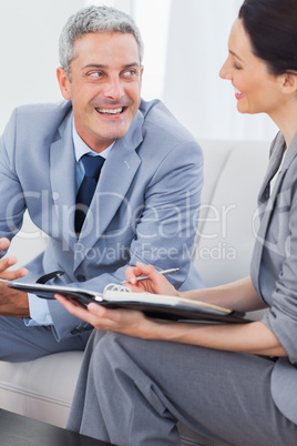 Cheerful business people working and talking together on sofa