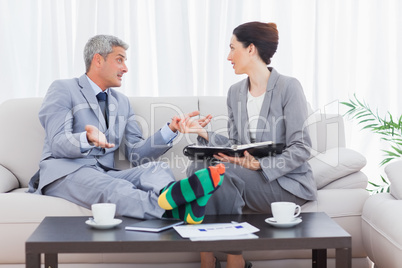 Funny businessman wearing stripey socks and talking with his col