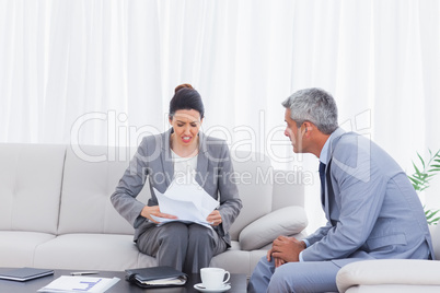 Stressed businesswoman holding documents and businessman trying