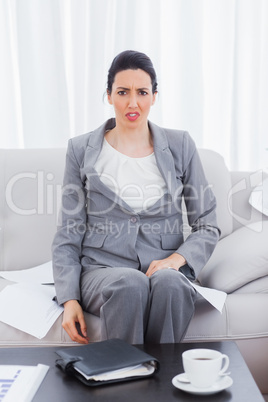 Outraged businesswoman sitting on sofa looking at camera