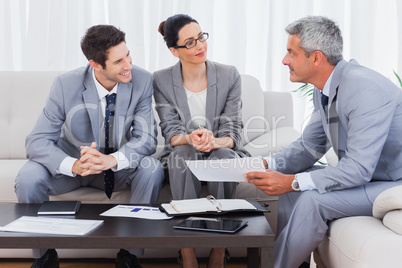 Smiling business people working and talking together on sofa