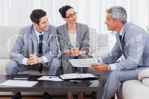 Smiling business people working and talking together on sofa