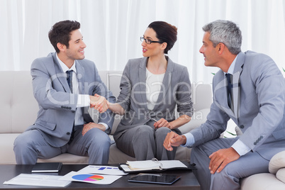 Happy business people working and talking together on sofa