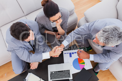 Business people sitting on sofa shaking hands during meeting