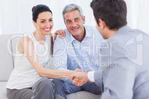Woman shaking hands with salesman sitting beside husband