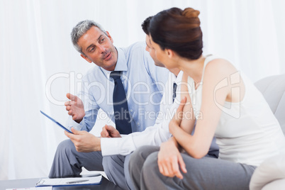 Concentrated business people talking about files on sofa