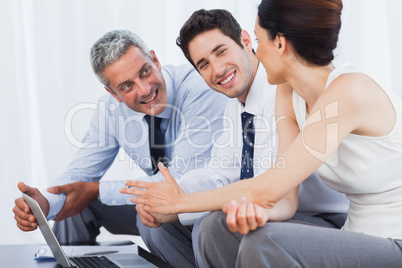 Smiling business people working with their laptop on sofa