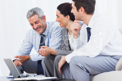 Cheerful business people working with their laptop on sofa