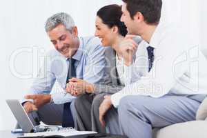 Cheerful business people working with their laptop on sofa