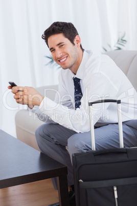 Happy businessman with suitcase and mobile phone