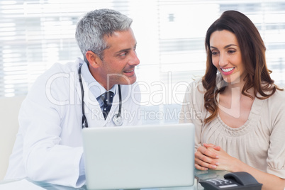 Docter showing something on laptop to his patient