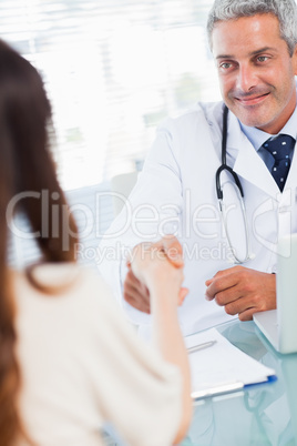 Smiling doctor shaking hands with his patient