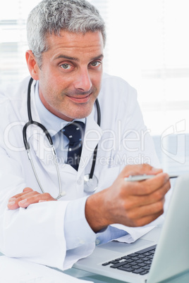 Smiling doctor watching something on his laptop