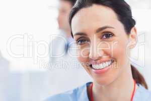 Smiling nurse looking at camera with a doctor behind her