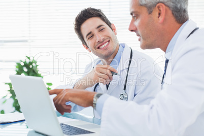 Doctors talking together about something on their laptop