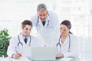 Team of concentrated doctors working together with their laptop