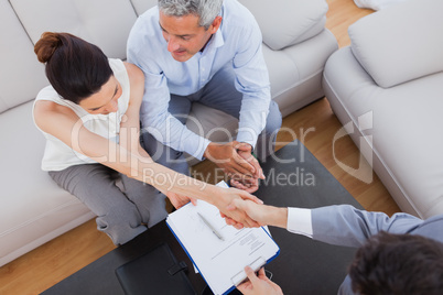 Businesswoman doing handshake with a businessman sitting on sofa