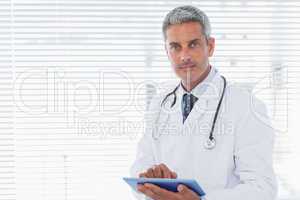 Doctor holding his tablet pc and looking at camera