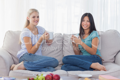 Friends drinking coffee together and smiling at camera