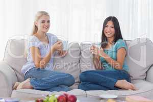 Friends drinking coffee together and smiling at camera