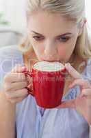 Blonde woman holding a mug and sipping from it