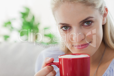 Blonde woman holding a red mug and smiling at camera