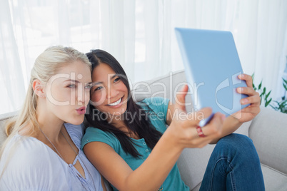 Two happy friends taking photo with tablet pc