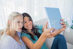 Two happy friends taking photo with tablet pc