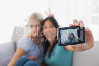 Two smiling friends taking photo with camera