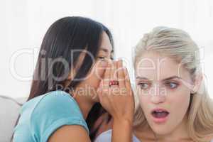 Friend telling secret to blonde woman