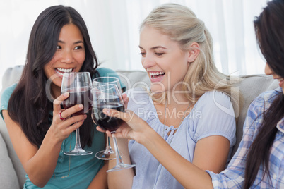 Happy friends toasting with red wine together