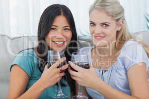 Smiling friends having red wine together looking at camera