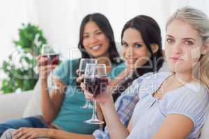 Cheerful friends having red wine together looking at camera