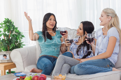 Cheerful friends having red wine together and talking