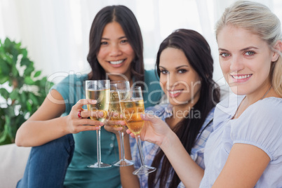 Cheerful friends enjoying white wine together smiling at camera
