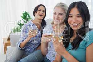 Happy friends having white wine together looking at camera