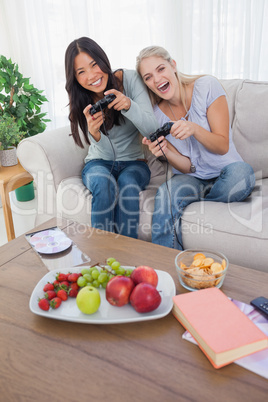 Happy friends playing video games and laughing