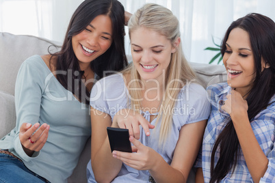 Laughing friends looking at smartphone