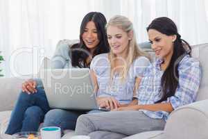 Smiling friends looking at laptop together