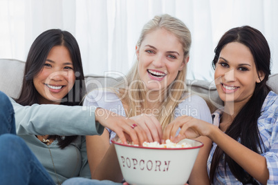 Friends sharing bowl of popcorn and watching tv