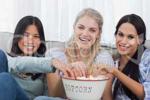 Friends sharing bowl of popcorn and watching tv