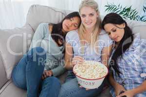 Friends dozing on blonde friends shoulders eating popcorn