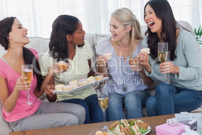 Friends drinking white wine and sharing cupcakes at party