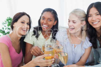 Friends toasting with white wine and smiling at camera