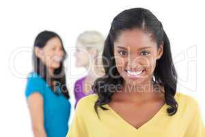 Smiling dark woman looking at camera with two women behind her