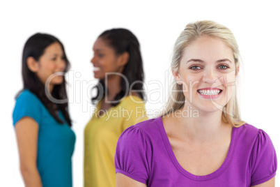 Smiling blonde woman looking at camera with two women behind her