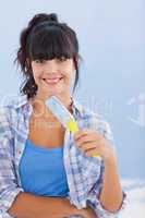 Pretty woman holding paint brush smiling at camera