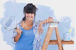 Woman holding paint roller leaning on ladder