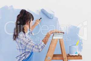 Woman using paint roller to paint wall